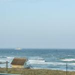 Meer mit Surfer und kleinem Haus im Vordergrund.