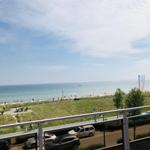 Blick auf Strand, Meer und Parkbereich mit Parkplätzen und Bäumen.