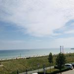 Meerstrand mit Strandpromenade und Parkplatz. Blick auf das Wasser und den Hafen.