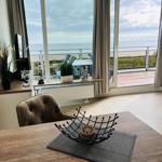 Wohnbereich mit Blick auf den Strand und das Meer durch große Fenster.