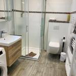 Badezimmer mit Dusche, Waschbecken und Toilette auf Holzdielen