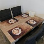 Esstisch mit vier Stühlen und Kaffeemotiv-Tischdecken.