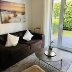 Wohnzimmer mit Sofa, Tisch und Blick auf den Garten.