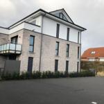 Moderne Villa mit Balkon und gepflastertem Vorplatz.