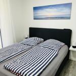 Schlafzimmer mit Doppelbett, Wandbild und Nachttischen.