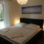 Schlafzimmer mit Bett, Wandbild und Türe zum Außenbereich.