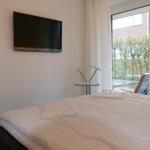 Schlafzimmer mit Bett, TV und Fenster zum Balkon.