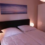 Schlafzimmer mit Doppelbett, Wandbild und zwei Nachttischen mit Lampen.