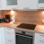Küche mit weißen Schränken, Holz Arbeitsplatte und Induktionskochfeld.