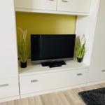 TV auf weißen Schrank mit Pflanzen und gelbem Hintergrund