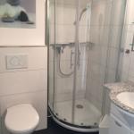 Badezimmer mit Duschkabine, Waschbecken und Toilette.