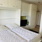 Schlafzimmer mit Bett, TV und weißen Schränken