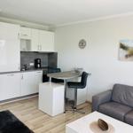 Wohnung mit Küche, Essbereich und Sofa. Wandbild und Uhr sichtbar.