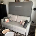 Gray sofa with cushions in front of wall with pictures and wall cabinet.