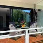 Terrace with two chairs and table, flowers and view into the house.