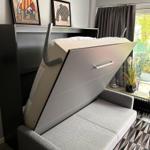 Sofa bed with storage, wall art, and window with curtains.