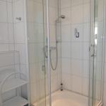 Duschkabine mit Glaswand und Duschbrause in weißer Badewanne