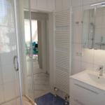 Badezimmer mit Dusche, Waschbecken und Heizkörper