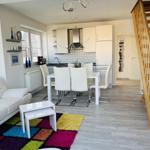 Wohn-Essbereich mit Küche, Sofa, Tisch und Holztreppe.