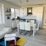 Wohn- und Essbereich mit weißem Sofa, Esstisch und Küchenzeile.