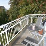 Balkon mit Tisch, Stühlen und Blick auf grüne Bäume.
