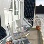 Terrasse mit Tisch und zwei Stühlen, Pflanzen und weißer Brüstung.