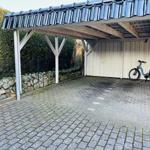 Carport mit blauem Dach und Fahrrad an der Wand.