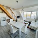 Wohn- und Essbereich mit weißem Sofa, Esstisch und Holztreppe.