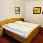 Ein Schlafzimmer mit Holzbett, zwei Nachttischen und Wandbildern.