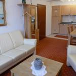 Wohnzimmer mit Sofa, Sessel und Küchenbereich