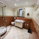Badezimmer mit Dusche, Waschbecken und Toilette. Fliesenwand und Boden.