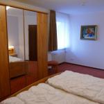 Schlafzimmer mit Doppelbett, Kleiderschrank und Fenster.
