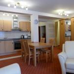 Küche mit Essbereich und Wohnzimmer mit weißen Sesseln und Holzmöbeln.