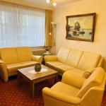 Wohnzimmer mit zwei Sofas, Sessel und Tisch. Wandbild und Fenster mit Vorhängen.