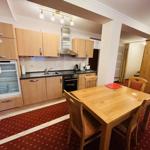Küche mit Essbereich, Holztisch und Stühle. Kühlschrank offen. Teppichboden.
