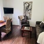 Wohnzimmer mit Sofa, Sessel, Esstisch und Wandbild