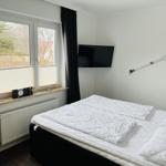 Schlafzimmer mit Bett, TV und Fenster mit Blick nach draußen.