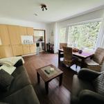 Wohnzimmer mit Essbereich, Küche und großem Fenster. Holzboden und wohnliche Einrichtung.