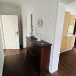 Eingangsbereich mit dunklem Schrank und Küchenbereich im Hintergrund.