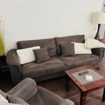 Ein Wohnzimmer mit braunem Sofa, Kissen und Holztisch.