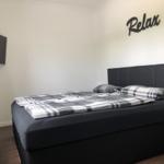 Schlafzimmer mit Bett, Wanddekoration und Fernseher.