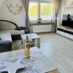 Living room with sofa, TV, and window overlooking trees.