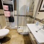 Bathroom with shower, sink, and towel warmer with towels.