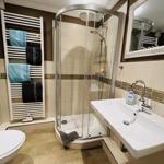 Bathroom with shower, sink, and towel radiator with towels.