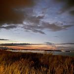 Cabin by water at sunset with illuminated horizon