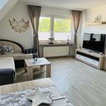 Living room with sofa, TV, and window with view of greenery.