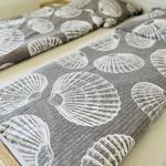 Two beds with gray bedspread featuring shell pattern.