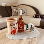 On the table, a bottle and a mug with maritime motifs are placed. In the background, there is a sofa with cushions.