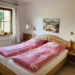 Doppelbett mit rosa Bettwäsche, Holzrahmen und Wandbild. Fenster mit Vorhängen.