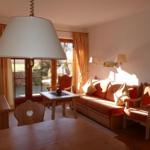 Wohnzimmer mit Sofa, Stühlen und Tisch. Durchgangstür und Fenster mit Vorhängen.